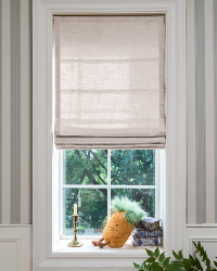 Window with beige roman shade, candle, and decorative items on a windowsill.