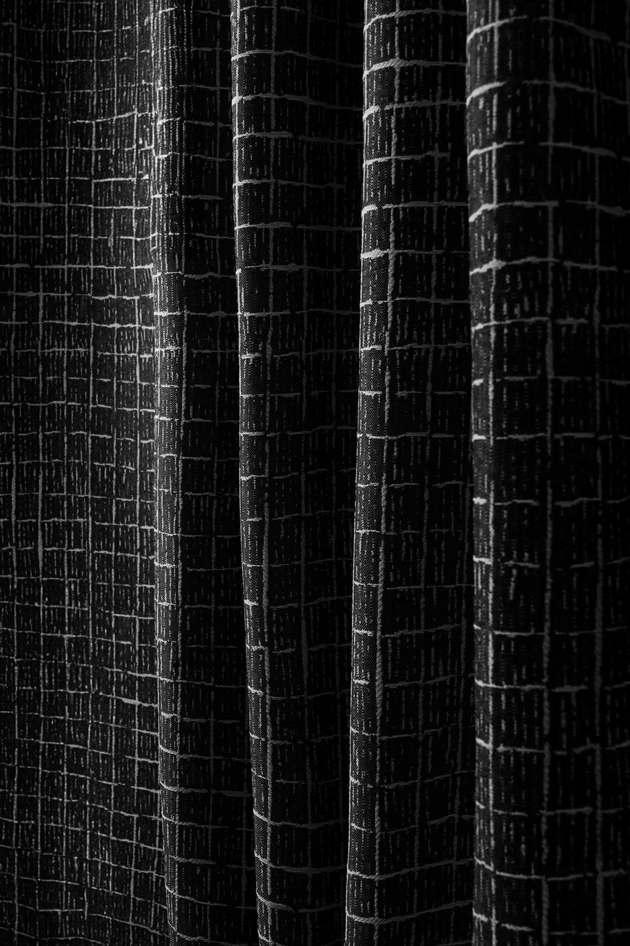 Detailed view of New York Grid patterned textured black fabric for custom outdoor curtain, highlighting waterproof material & elegant folds.