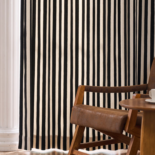 Black and white striped curtain with a wooden chair and table in front