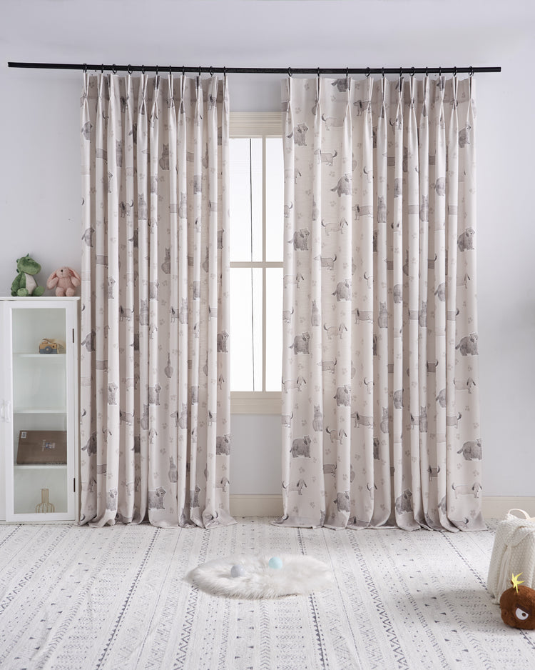 TheHues custom kid's drapery: light airy fabric with playful dog & paw print pattern, pinch pleat, framing a bright nursery window.