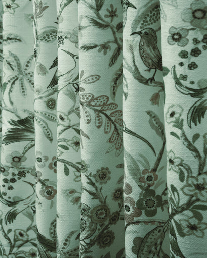 Close-up of TheHues custom Peacock linen blend heavyweight drapery fabric, with elegant floral and bird patterns on pleated folds.