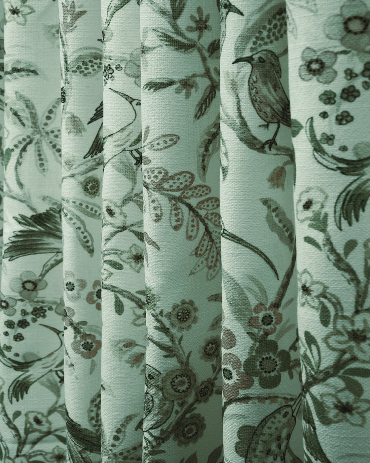 Close-up of TheHues custom Peacock linen blend heavyweight drapery fabric, with elegant floral and bird patterns on pleated folds.