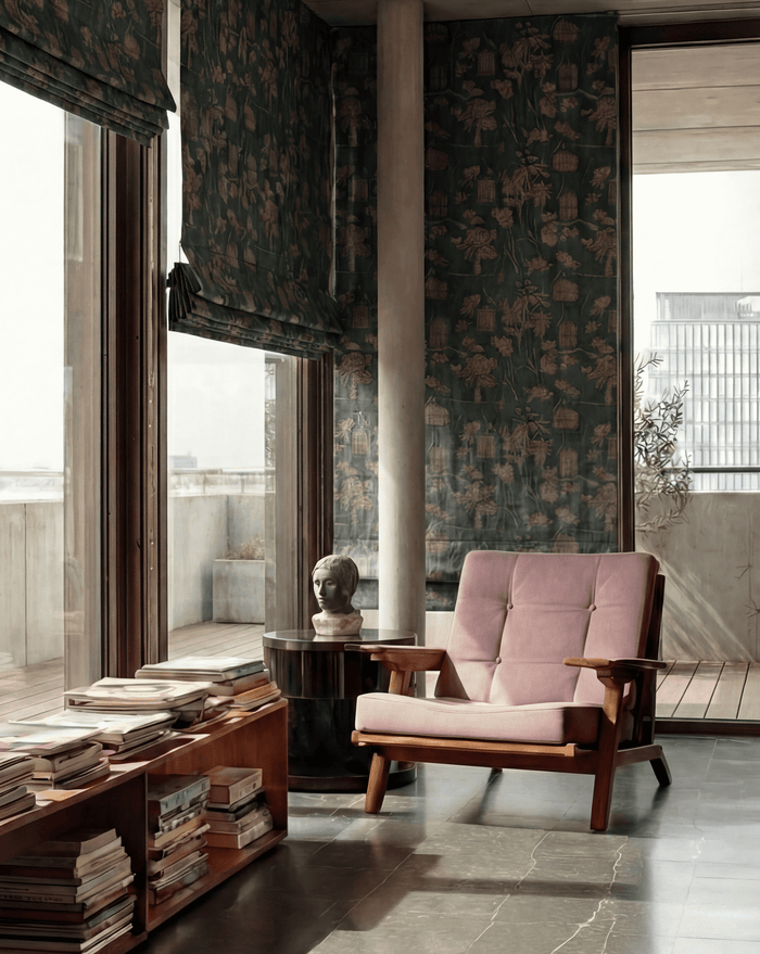 Seeker flat fold floral cordless custom Roman shades on floor-to-ceiling windows in a modern room with a pink chair.