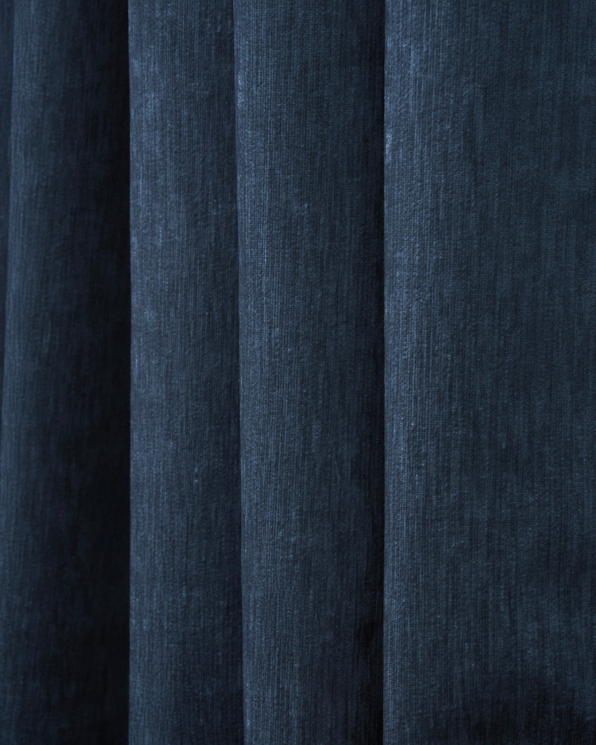 Close-up of dark navy velvet custom curtain fabric with soft folds, highlighting the luxurious texture and blackout quality.