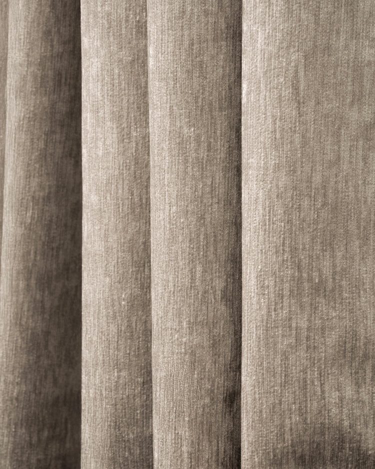Close-up of Quinn 100% Blackout OEKO Heavyweight Velvet custom curtain fabric, showcasing plush texture and soft, vertical folds in taupe.