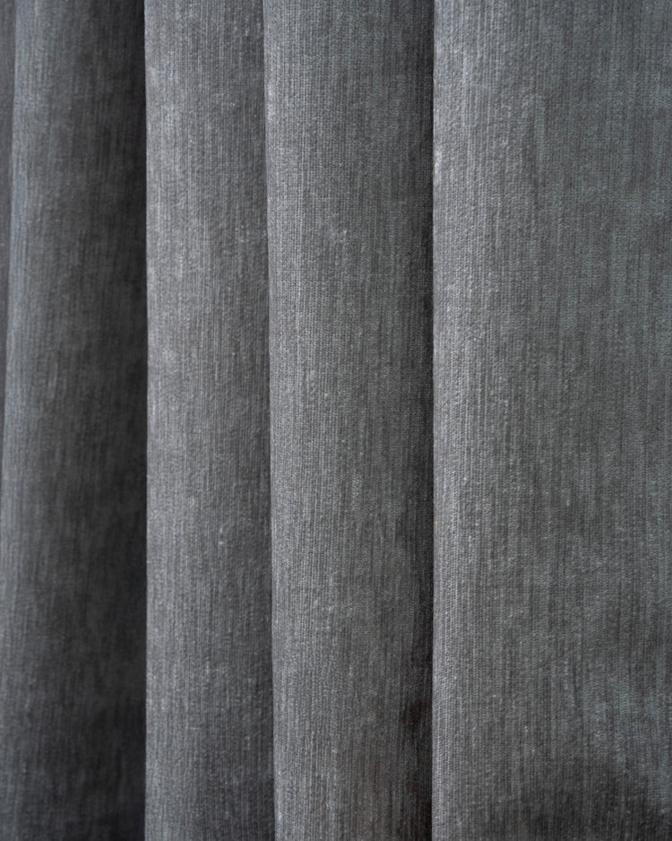 Luxurious dark gray heavyweight velvet custom blackout curtain fabric, showcasing its rich, vertical texture and elegant folds.