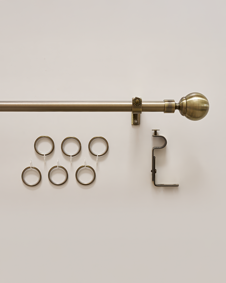 Antique brass custom curtain rod with elegant ball finial, mounting bracket, and six matching drapery rings for window treatments.