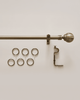 Antique brass custom curtain rod with elegant ball finial, mounting bracket, and six matching drapery rings for window treatments.