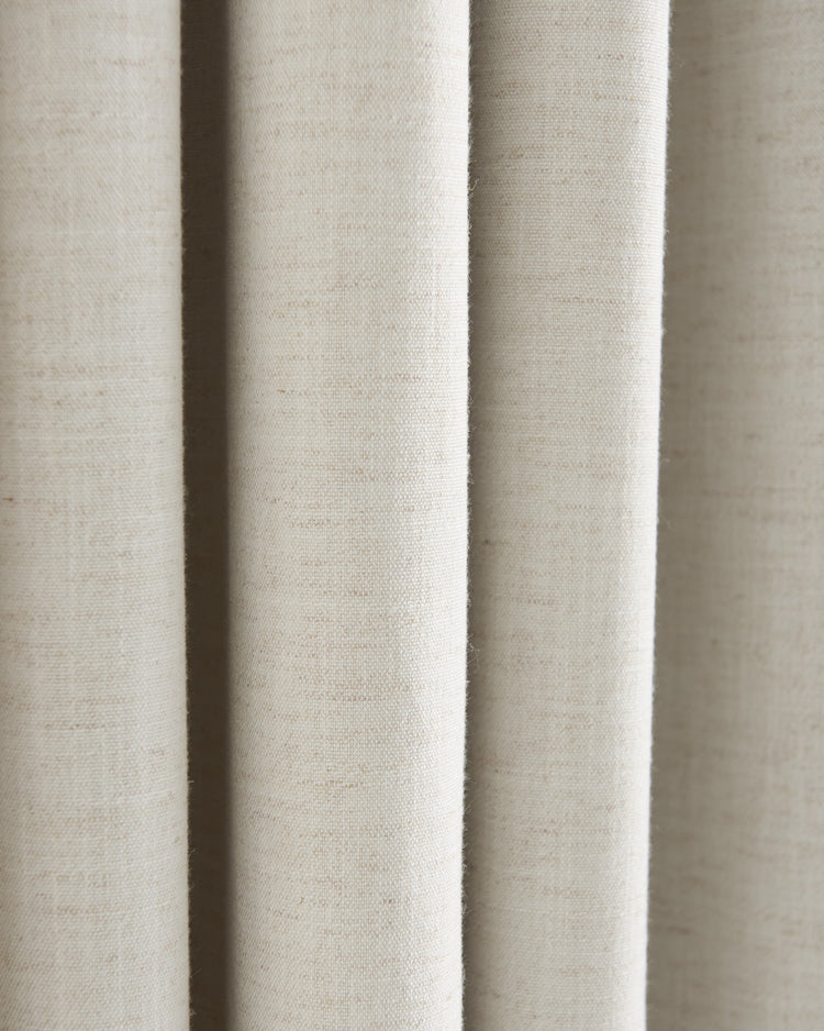 Close-up of the light beige linen blend fabric of a Sally custom blackout curtain, highlighting its luxurious texture and soft drapery folds.