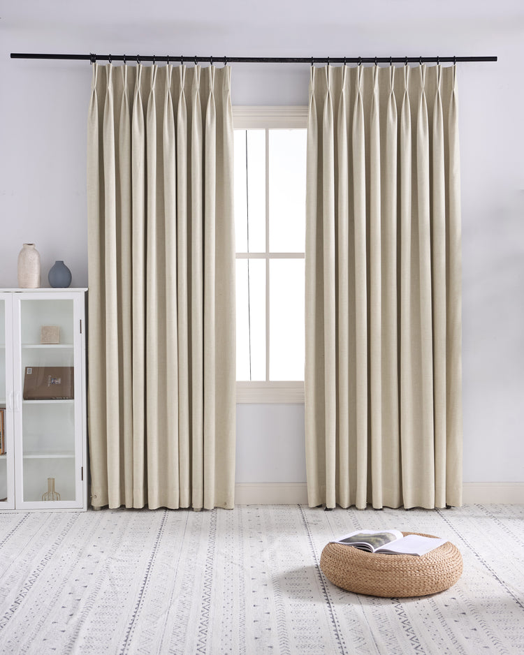 Custom light beige linen blend blackout curtains with tailored pinch pleats, showcasing rich texture for superior light control.