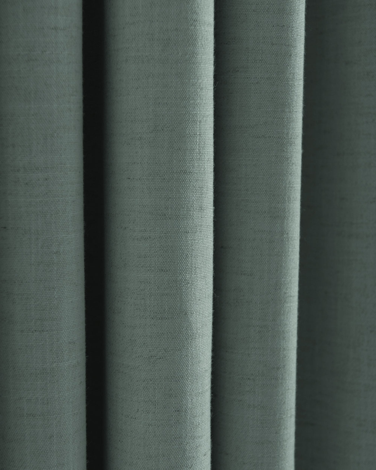 Close-up of draped Sally Linen Blend fabric in muted green, revealing its natural weave and elegant texture for custom drapery.