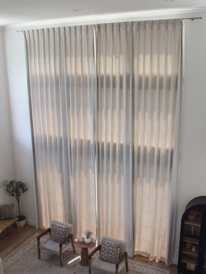 Custom Sally Linen Blend drapery, floor-to-ceiling, with tailored pleats, beautifully diffusing natural light in a high-end living room.