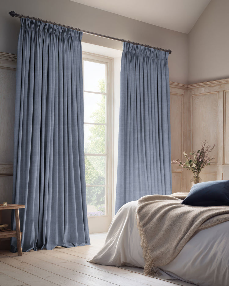 Tailored blue-grey 100% blackout linen blend custom drapery with pinch pleats in a sophisticated bedroom.