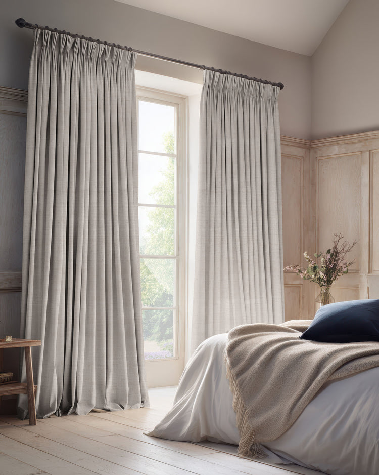 Elegant gray blackout linen blend custom curtains with pleated header frame a bedroom window, offering light control & sophisticated home decor.