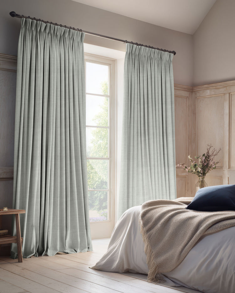 Serene bedroom with light grey Sally blackout linen blend custom curtains, floor-length and pleated, offering stylish light control.