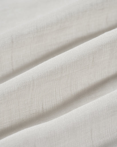Close-up of a folded Yarn Linen Look Sheer Custom Curtain fabric, revealing its subtle texture & translucent weave for elegant window treatments.