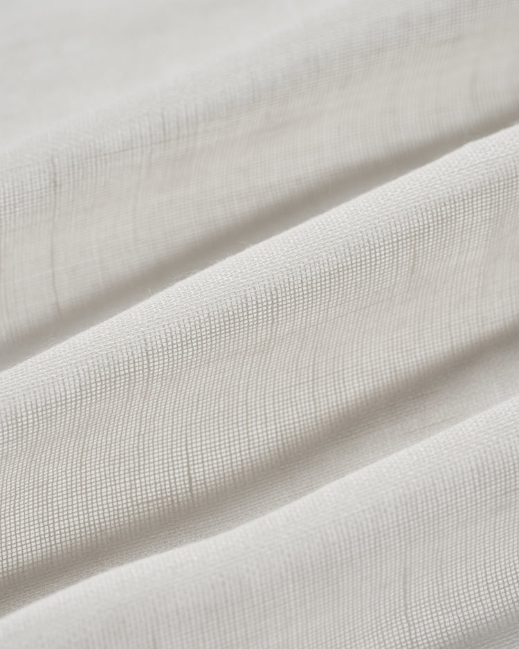 Close-up of a folded Yarn Linen Look Sheer Custom Curtain fabric, revealing its subtle texture & translucent weave for elegant window treatments.