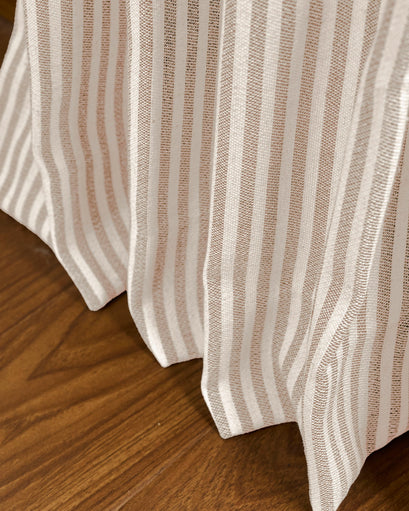 Close-up of Milo Linen Blend custom curtain fabric, showcasing natural beige & white vertical stripes & intricate texture on a wood floor.