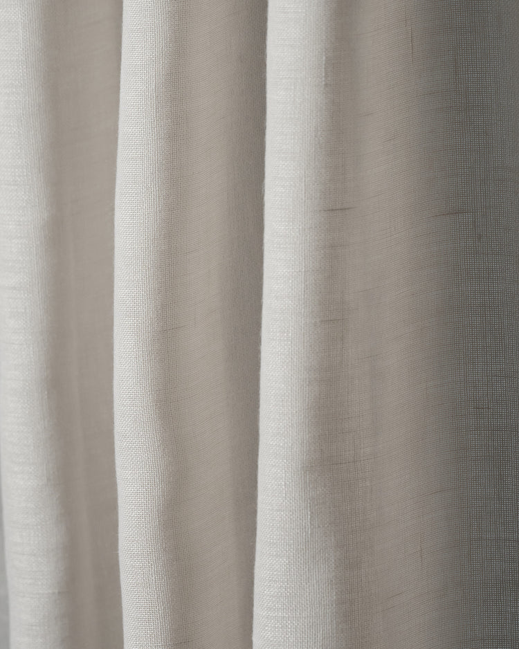 Close-up of a draped cream linen look sheer fabric swatch, showcasing its slubbed texture for elegant custom window treatments.