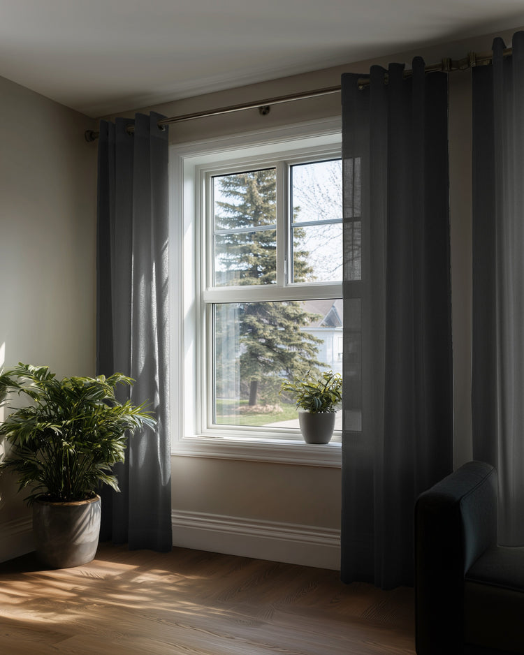 Custom dark grey yarn linen look sheer grommet curtains, filtering sunlight through a window, providing privacy & elegant home decor.