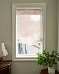 Relaxed custom yarn sheer Roman shade on a window, offering soft light filtering and sophisticated home aesthetics.