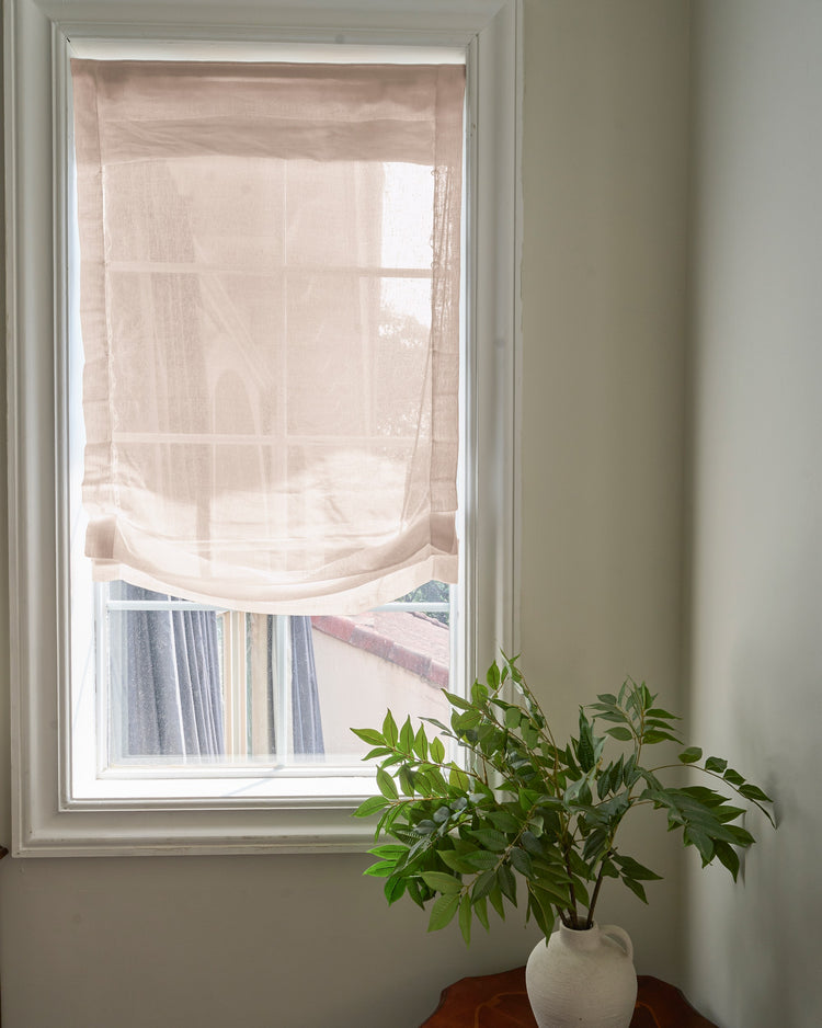 Elegant custom sheer yarn relaxed Roman shade in a soft beige hue, offering gentle light diffusion & privacy through a window.