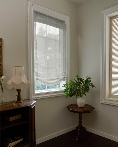 Yarn sheer relaxed custom Roman shade on a bright window, offering soft light and privacy in a sophisticated home decor setting.
