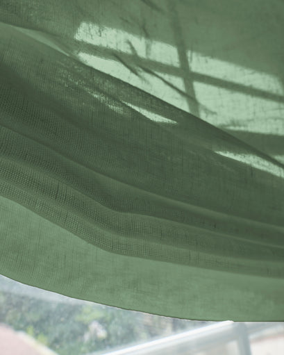Close-up of a soft green yarn sheer relaxed custom Roman shade fabric, highlighting its woven texture & gentle light filtering.