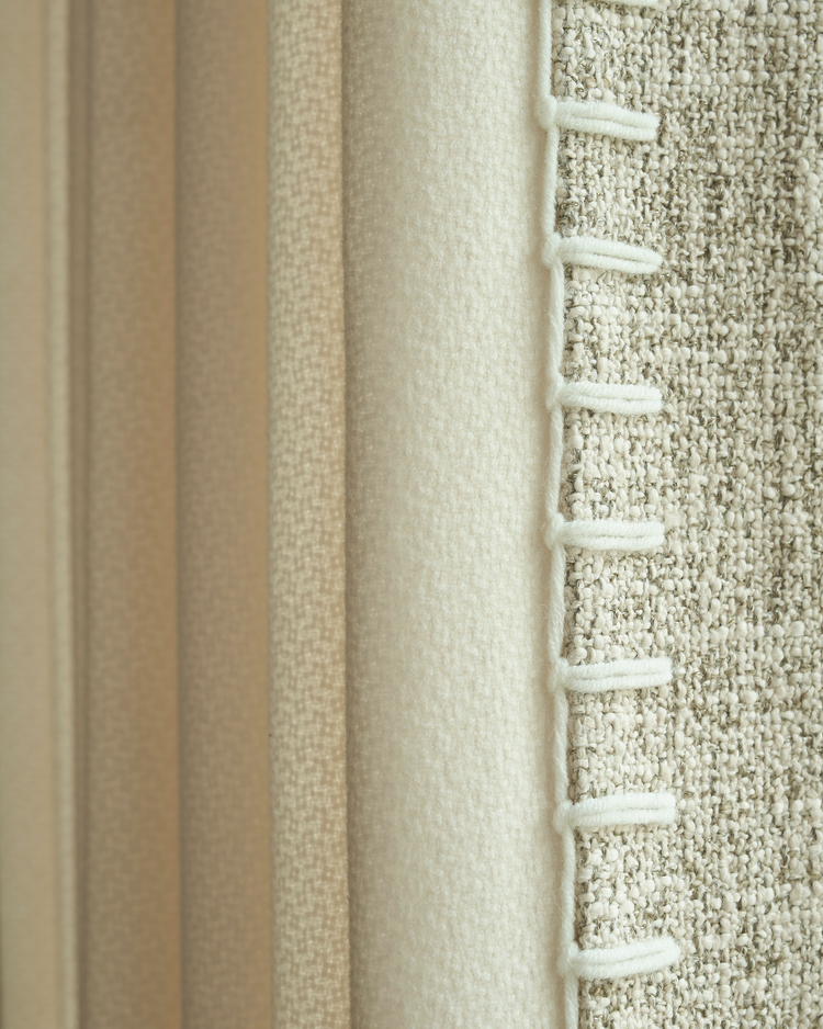 Detail of Zane custom curtain: textured oatmeal fabric with exquisite white looped trim, next to a soft cream panel.