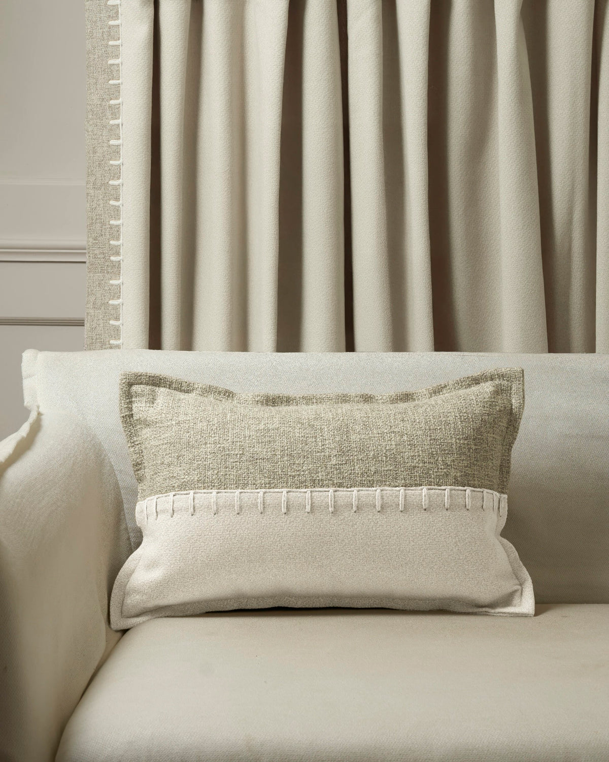 Luxe Zane wool blend lumbar pillowcase on sofa with bold white yarn-stitch trim, complementing matching custom window treatments.