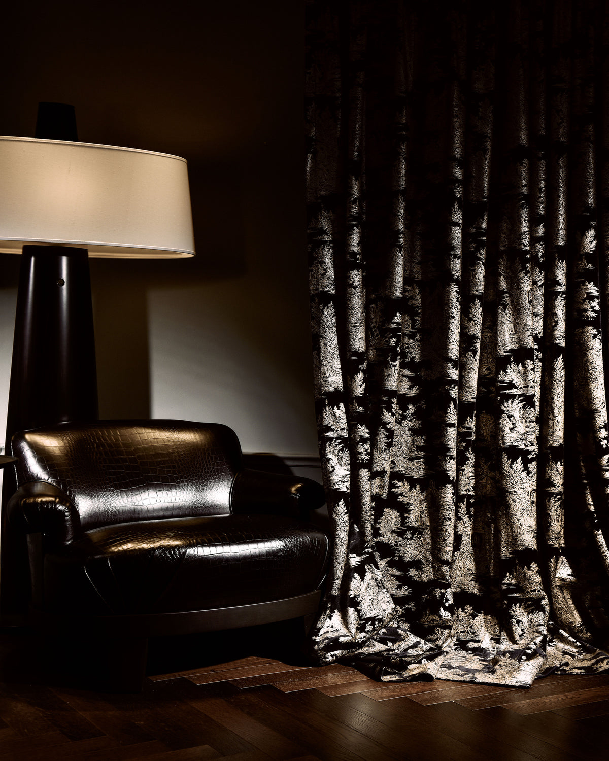 Dark Zen Foil Printed Velvet custom drapery with elegant pattern beside a luxurious leather armchair, showcasing high-end home decor.