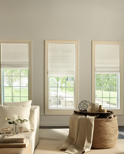 Three custom Zoe Flat Fold Roman Shades in cream linen-look fabric, offering tailored light control and sophisticated window treatment in a bright living room.