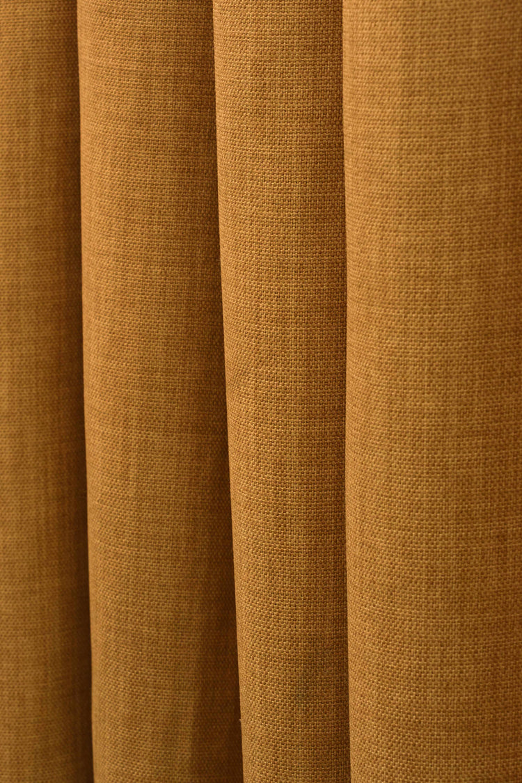 Close-up of Zoe linen look custom curtain fabric in a warm golden brown, highlighting its soft, textured weave and elegant drape.