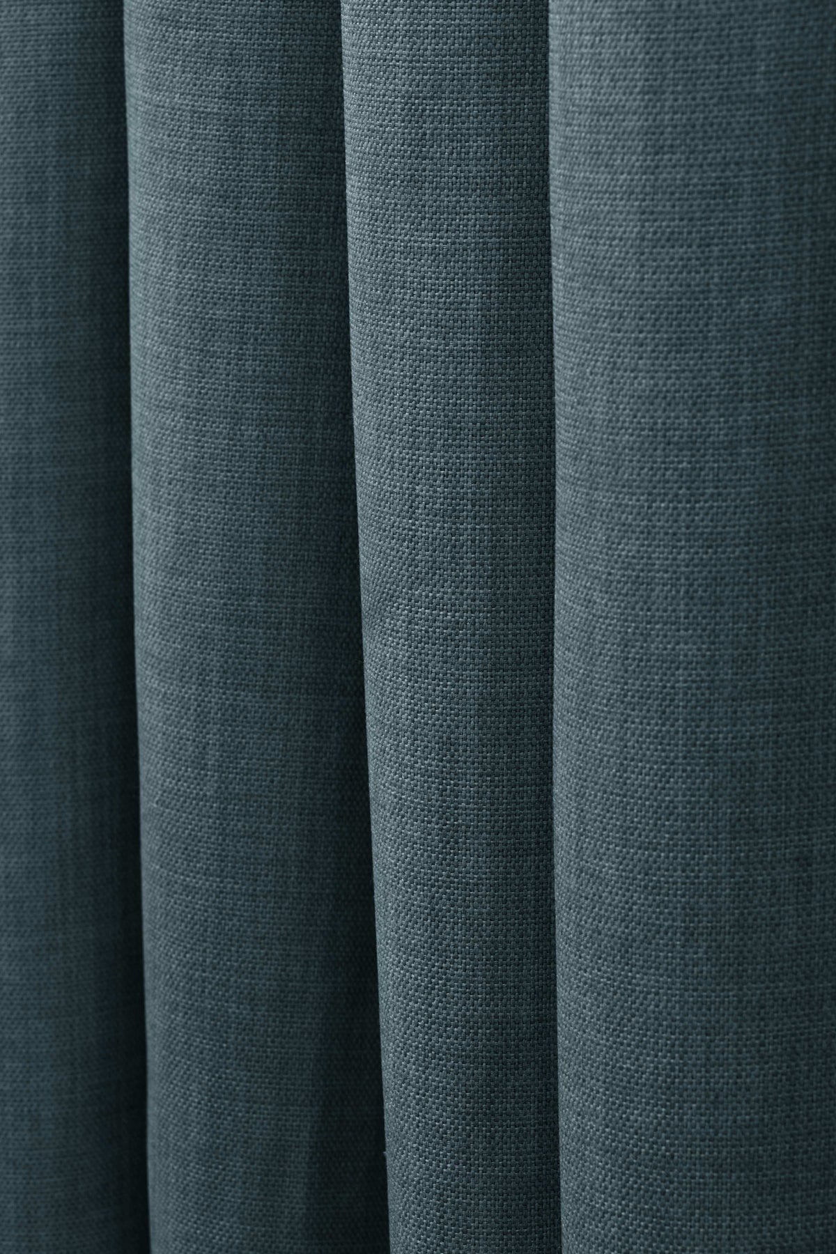 Close-up of soft deep teal custom linen look curtain fabric, showing its intricate weave and elegant folds for tailored window treatments.