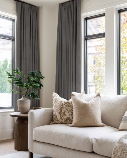 TheHues Zoe dark grey 100% Blackout Linen Look Custom Curtains with tailored pleats framing large living room windows.